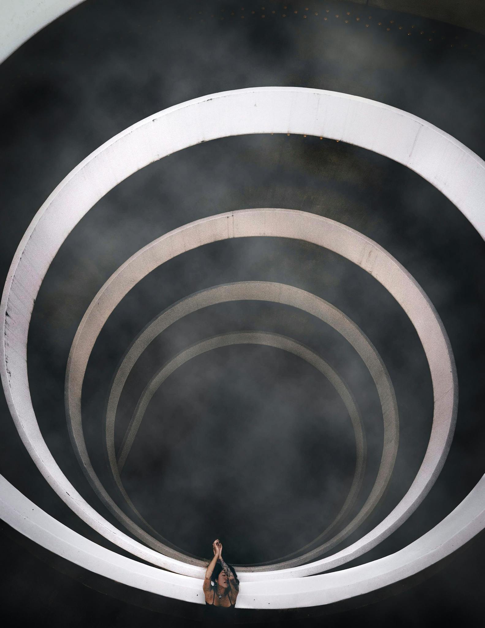 A dramatic top-down view of a spiral staircase enveloped in smoke, showcasing modern architectural style.